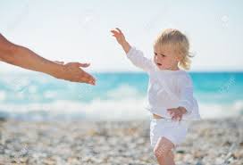 baby reaching with hand on beach